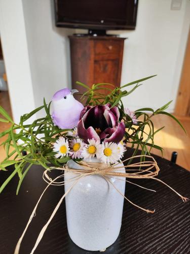 a vase filled with flowers and a bird on a table at Au chant des oiseaux - rouge gorge in Varen
