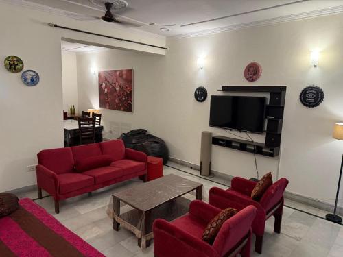 a living room with red furniture and a flat screen tv at Bienvenue Homestay in Panchkula