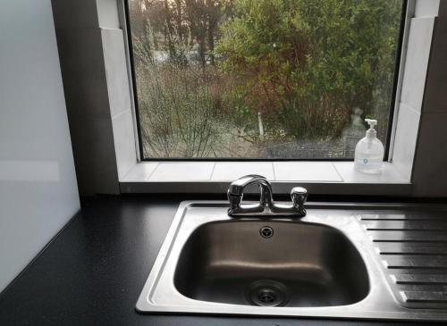 a sink in front of a window with a bottle of soap at Nature Retreat - Sleeps 4 & Wild Ponies in Tullaghanbaun