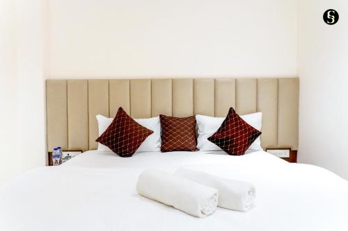 a large white bed with red and brown pillows at Shivaay Inn Paying Guest House in Varanasi
