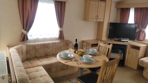 a living room with a table and a couch at Sand Le Mere Caravan in Tunstall