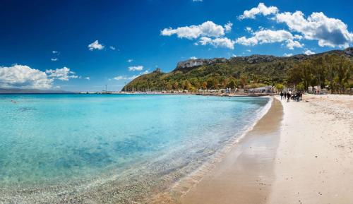 a beach with people walking on the sand and the water at B&B Antica Villa in Quartu SantʼElena