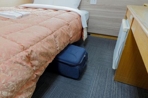a bedroom with a bed with a blue ottoman under it at Hotel Maira in Okayama