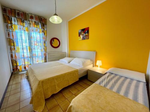 a bedroom with two beds and a yellow wall at Homely flat with shared pool in Porto Santa Margherita di Caorle