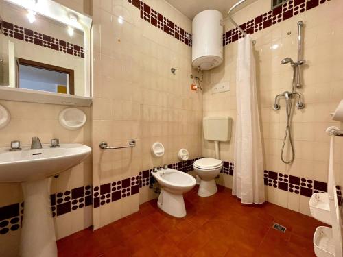 a bathroom with a toilet and a sink and a shower at Homely flat with shared pool in Porto Santa Margherita di Caorle