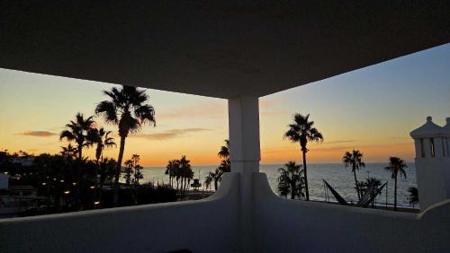 a view of a sunset from a balcony with palm trees at Apartment in the center of La Cala de Mijas with Sea Views in Mijas