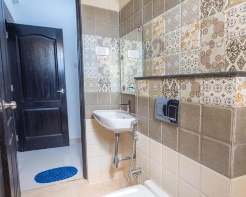 a bathroom with a sink and a shower with a door at 4Bedroom Villa With shared pool in Nerul