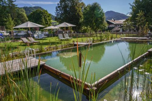 a pool of water with chairs and umbrellas at Beim Nuihausa in Reit im Winkl