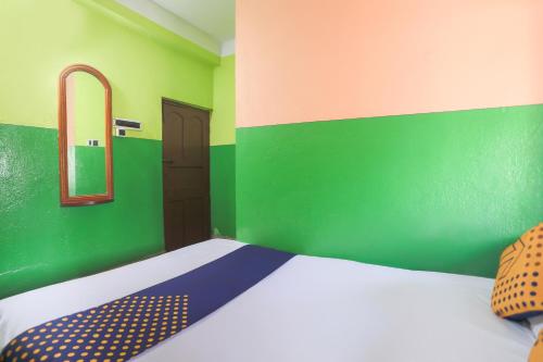 a bedroom with a bed with a green wall and a mirror at Hotel O New Heaven in Murshidābād