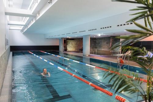 a woman swimming in a large swimming pool at Hotel Kö59 Düsseldorf - Member of Hommage Luxury Hotels Collection in Düsseldorf