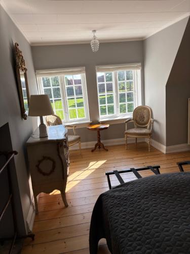 a bedroom with a bed and chairs and windows at Risinge Herregård in Ullerslev