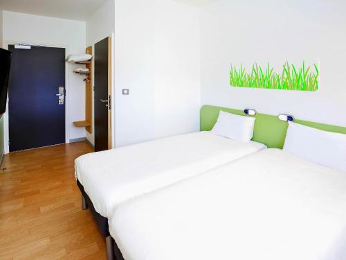 a pair of beds in a room with at Ibis Budget Sarrebourg Buhl in Sarrebourg