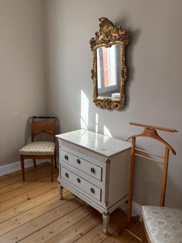 a room with a dresser and a mirror and a chair at Risinge Herregård in Ullerslev
