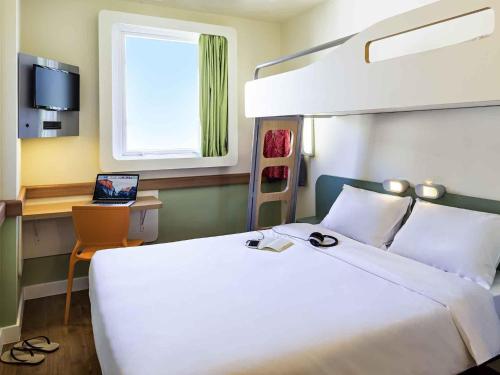 a hotel room with a bed and a laptop on a desk at ibis budget RJ Praia de Botafogo in Rio de Janeiro