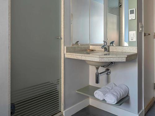 a bathroom with a sink and a mirror and towels at ibis budget RJ Praia de Botafogo in Rio de Janeiro