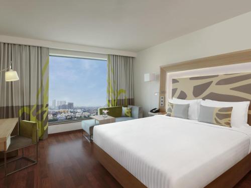 a hotel room with a bed and a large window at Novotel Chennai OMR in Chennai