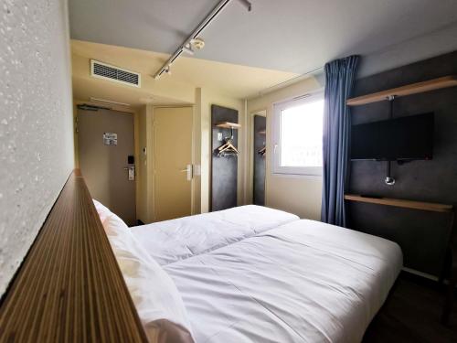 a bedroom with a white bed and a television at ibis Budget Lille Marcq En Baroeul in Marcq-en-Baroeul