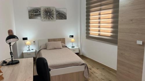 イスナハルにあるEncanto en Iznájar con terraza y vistas a la montañaのベッドルーム1室(ベッド1台、ランプ2つ、窓付)