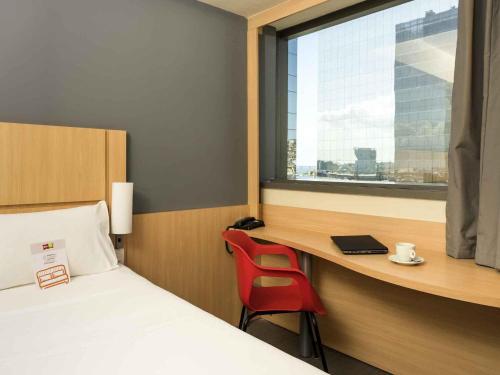 a bedroom with a bed and a desk with a red chair at ibis Rio Porto Atlantico in Rio de Janeiro
