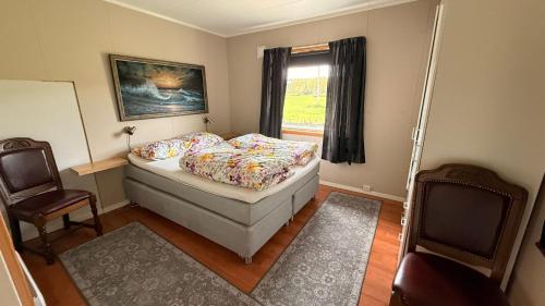 a bedroom with a bed and two chairs and a window at Koselig hus i sentrum av Olderfjord in Russenes