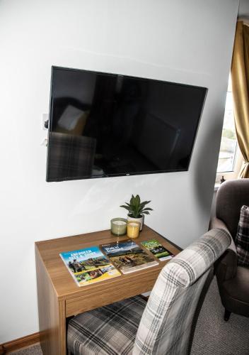 a living room with a table with a tv on the wall at Free Parking, Near Airport, Aberdeen Uni and ARI in Aberdeen