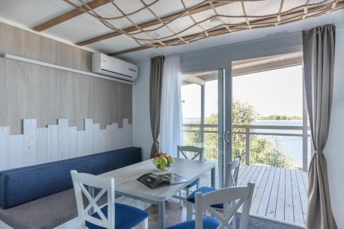 a dining room with a table and chairs and a balcony at Maistra Camping Veštar Mobile homes in Rovinj