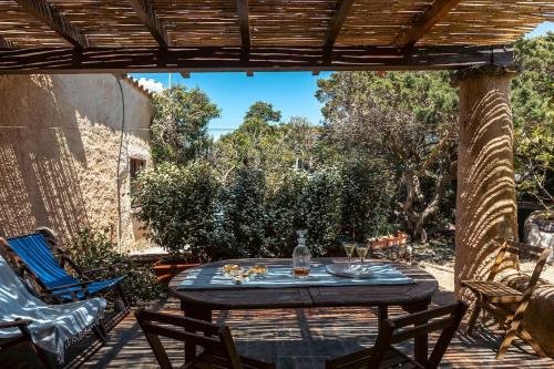 un patio con tavolo e sedie sotto un pergolato di Vicinissima alla spiaggia della Pelosa a Stintino
