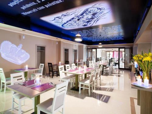a restaurant with tables and chairs and a large screen at Ibis Styles Gniezno Stare Miasto in Gniezno