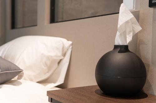 a black vase sitting on a table next to a bed at Minato Mirai 15 min 1BR 1BA in Nishi-hiranumachō