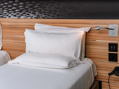 a bed with white pillows in a hotel room at Novotel London Canary Wharf in London