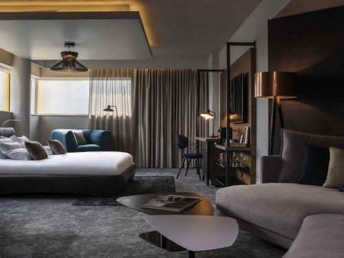 a hotel room with a bed and a couch and a table at Novotel London Canary Wharf in London