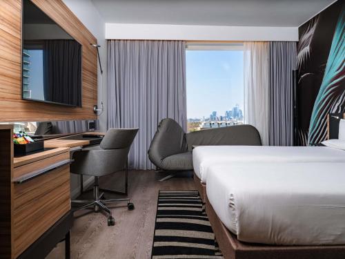 a hotel room with a bed and a desk and chair at Novotel London Canary Wharf in London