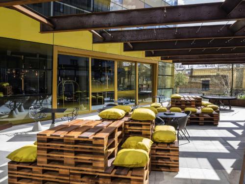 a patio with yellow pillows and tables and windows at Novotel London Canary Wharf in London