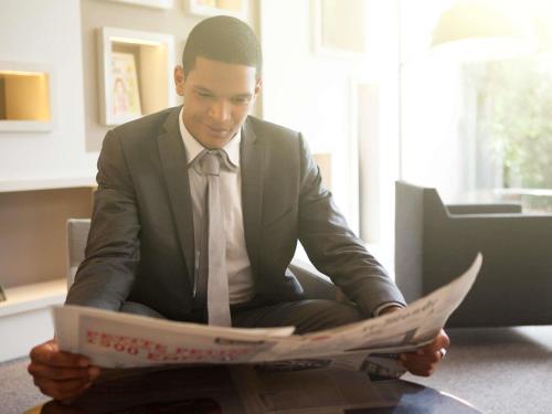 a man in a suit and tie reading a newspaper at Novotel London Canary Wharf in London