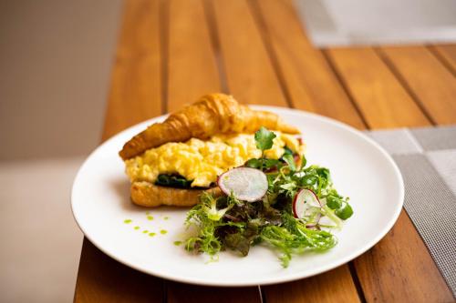 a white plate with a breakfast sandwich and a salad at The Daha Luxury Villas in Seminyak