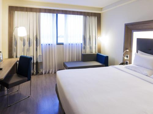 a hotel room with a large bed and a desk at Novotel RJ Porto Atlantico in Rio de Janeiro