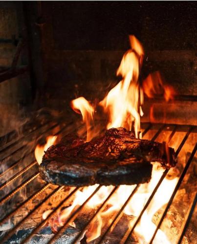 a piece of meat is cooking on a grill at Hôtel Restaurant La Caravelle in Sari Solenzara