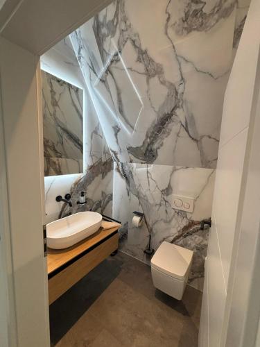 a marble bathroom with a sink and a toilet at Chalet NATURTRAUM in Runkel