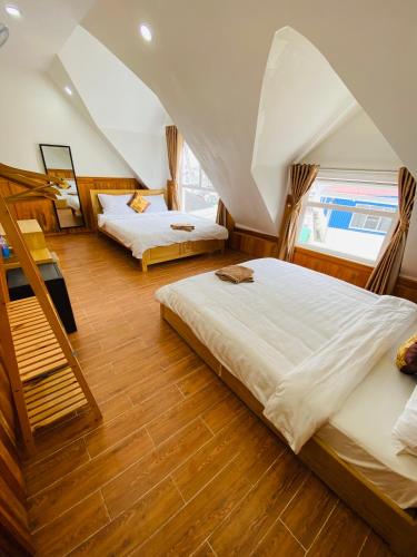 a bedroom with two beds and two windows at Khách Sạn Bình Nguyên Đà Lạt in Da Lat