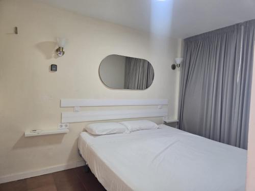Un dormitorio con una cama blanca y un espejo. en Los Molinos 735, en Maspalomas