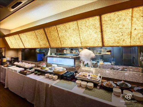 a buffet line in a restaurant with a chef in the kitchen at Daiwa Roynet Hotel Hamamatsu in Hamamatsu