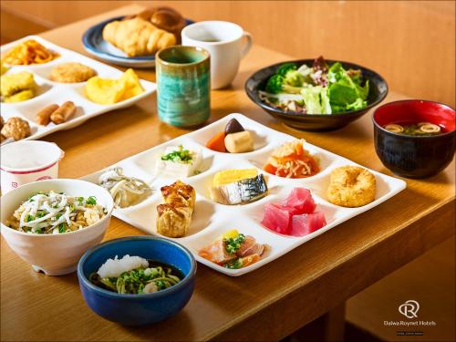 a table with plates of food and bowls of food at Daiwa Roynet Hotel Hamamatsu in Hamamatsu