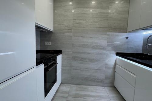 a kitchen with white cabinets and a black stove at Luxury apartment Benalmadena First line in Benalmádena