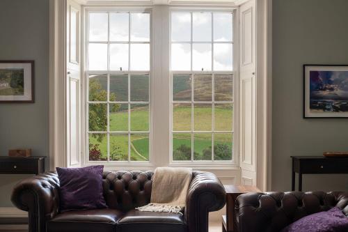 a living room with a leather couch and a large window at Quarter House in Broughton