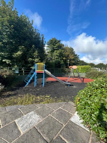 Un parque infantil con un tobogán azul y un columpio. en 61, Stowford Gardens, en Combe Martin