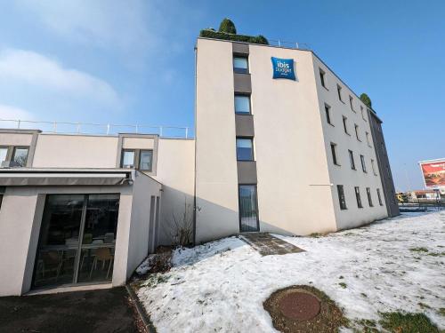 a building with snow in front of it at Ibis Budget Clermont Ferrand - Le Brezet - Aeroport in Clermont-Ferrand