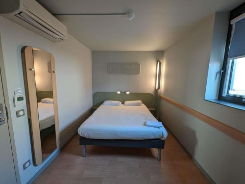 a small room with a bed and a mirror at Ibis Budget Clermont Ferrand - Le Brezet - Aeroport in Clermont-Ferrand