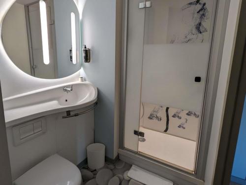 a bathroom with a sink and a mirror and a toilet at Ibis Budget Clermont Ferrand - Le Brezet - Aeroport in Clermont-Ferrand