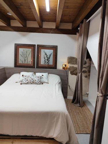 a bedroom with a white bed with two pictures on the wall at Lebari in Bérriz