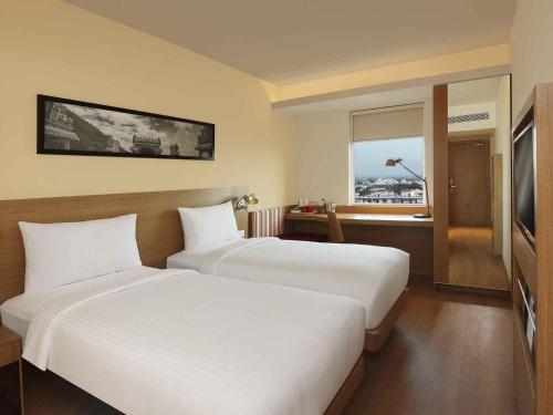 a hotel room with two beds and a window at ibis Coimbatore City Centre - An Accor Brand in Coimbatore
